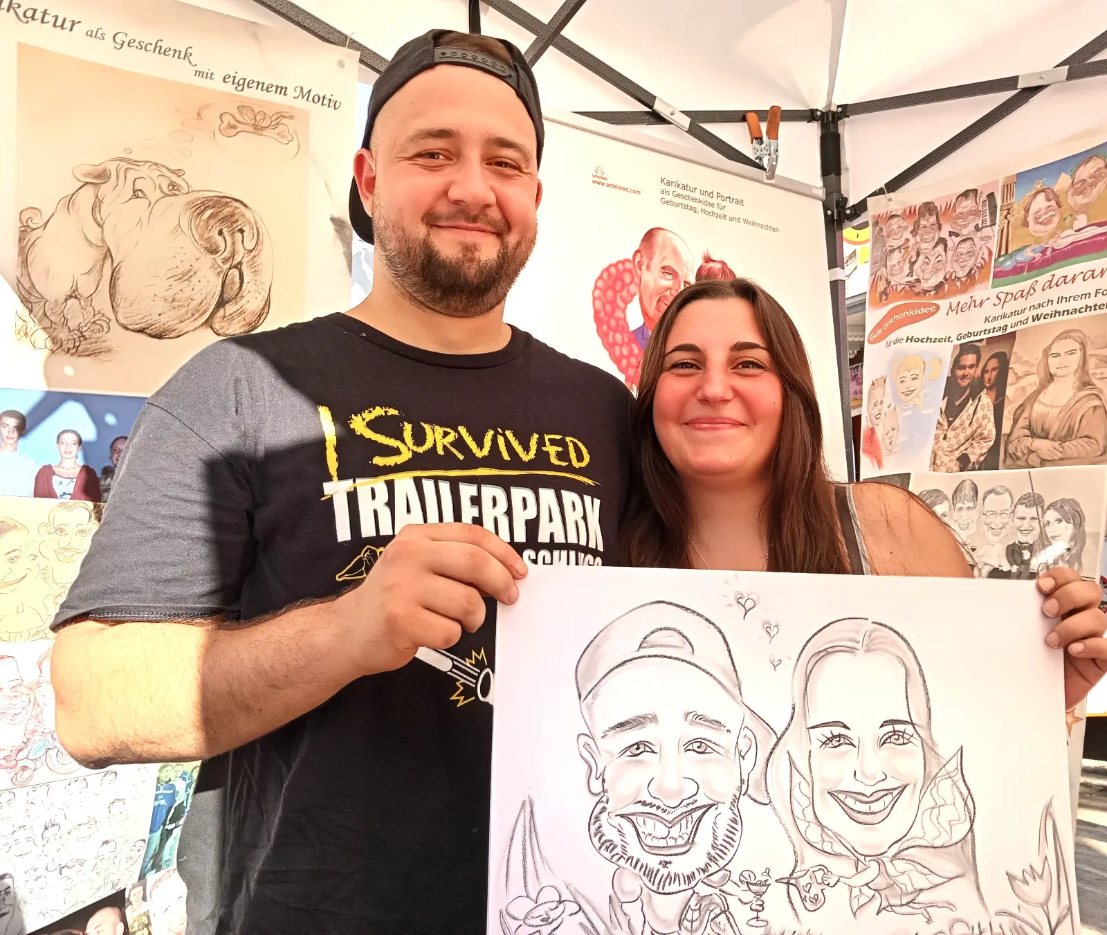 un couple heureux montre fièrement son portrait caricatural personnalisé lors d une foire d art au luxembourg entouré d autres oeuvres de bande dessinée